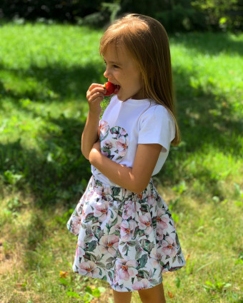 dziewczynka w letniej sukience jedząca truskawkę